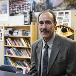 man with mustache in suit in front of bookcases