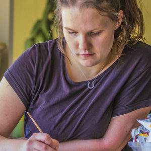 girl in purple shirt writing with a pencil
