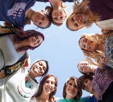 group of teenage girls of different races standing in circle and looking directly at the viewer